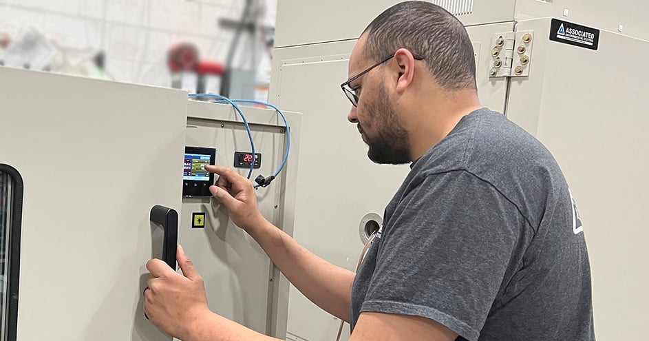 An AES employee configuring the settings of an environmental test chamber.