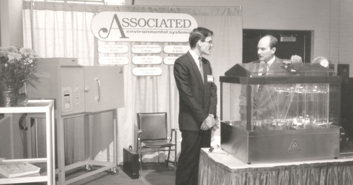 historic photograph of John O'Rourke standing next to AES' MX series salt spray test chamber