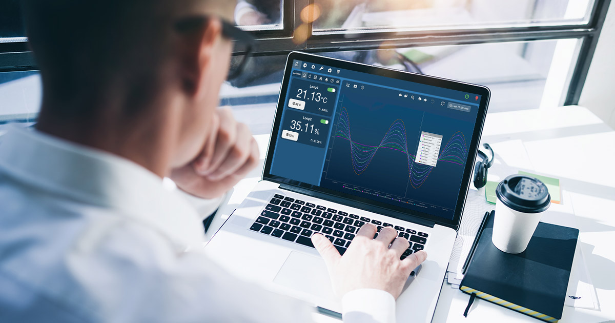 A person typing on a laptop while looking at a AES dashboard.