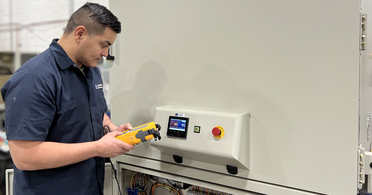 An AES maintenance technician inspecting an environmental test chamber.