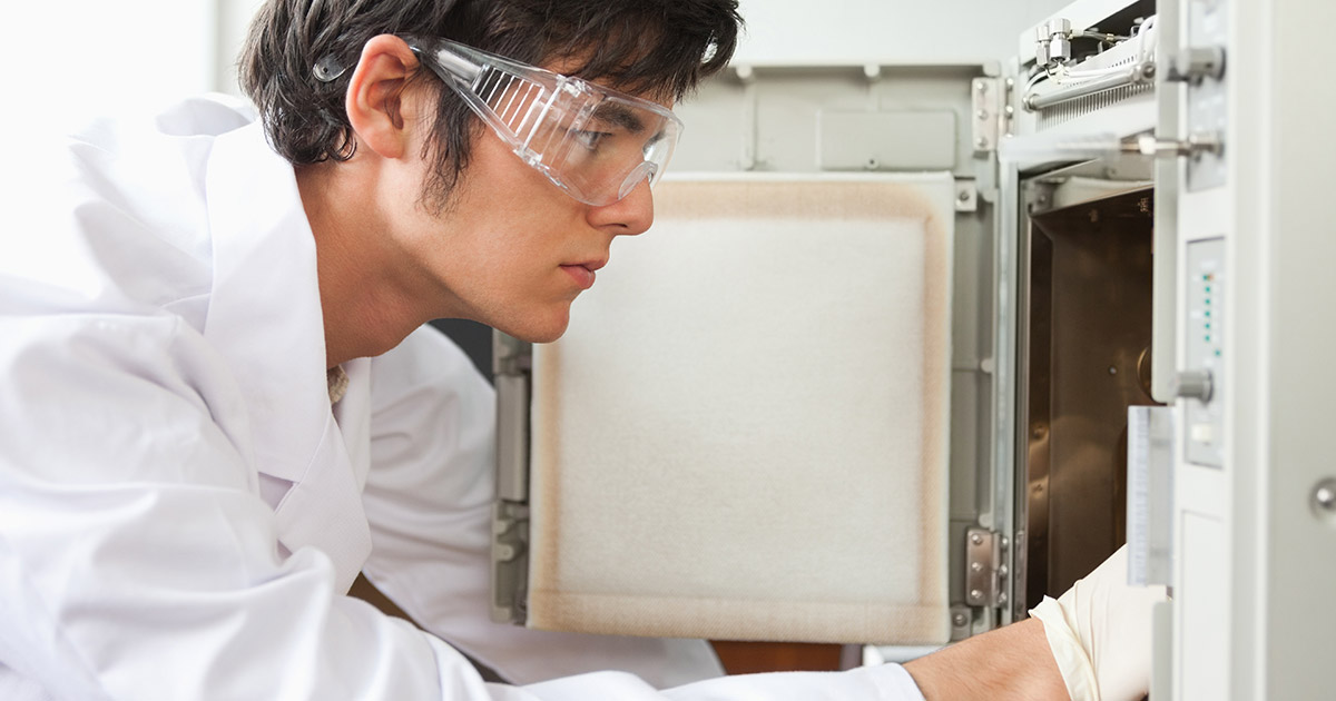 scientist reaching into an open benchtop test chamber