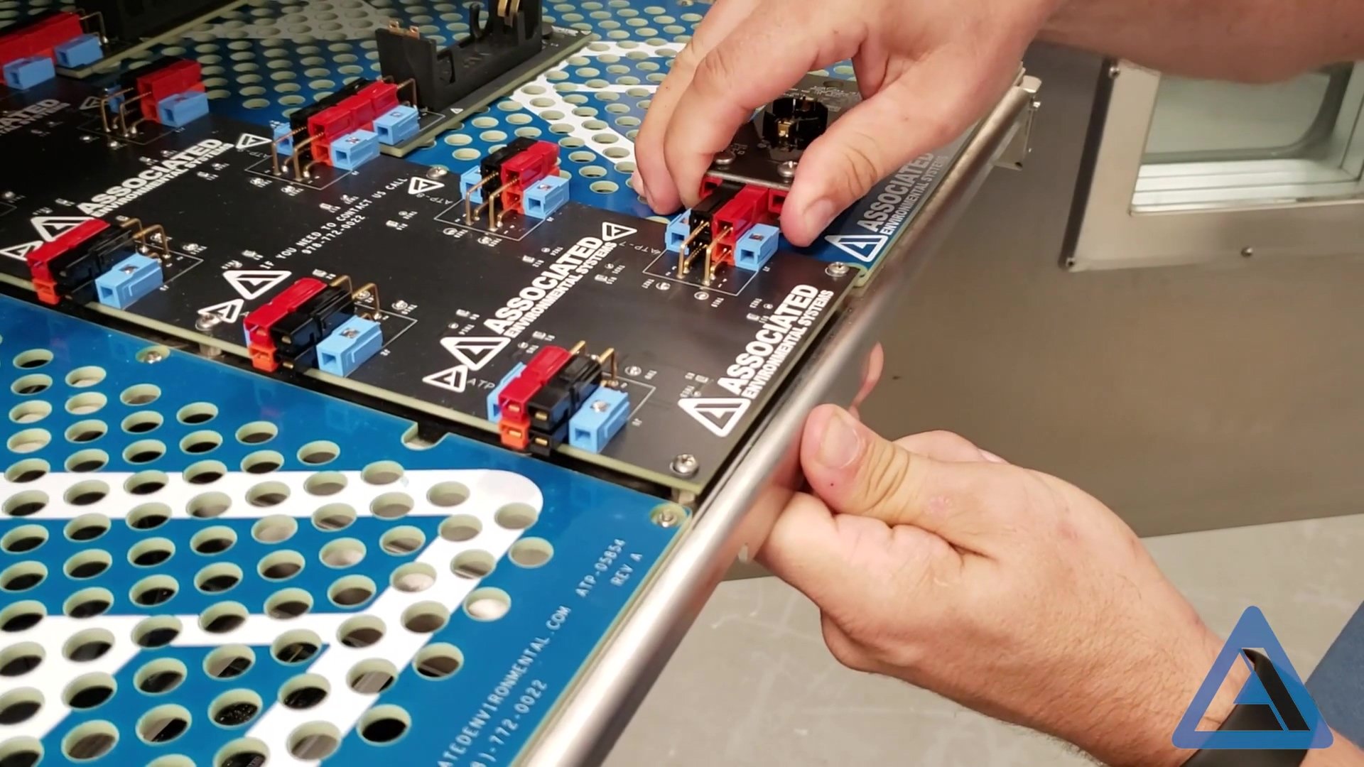 A closeup of a persons hands installing a clip on a battery testing chamber.